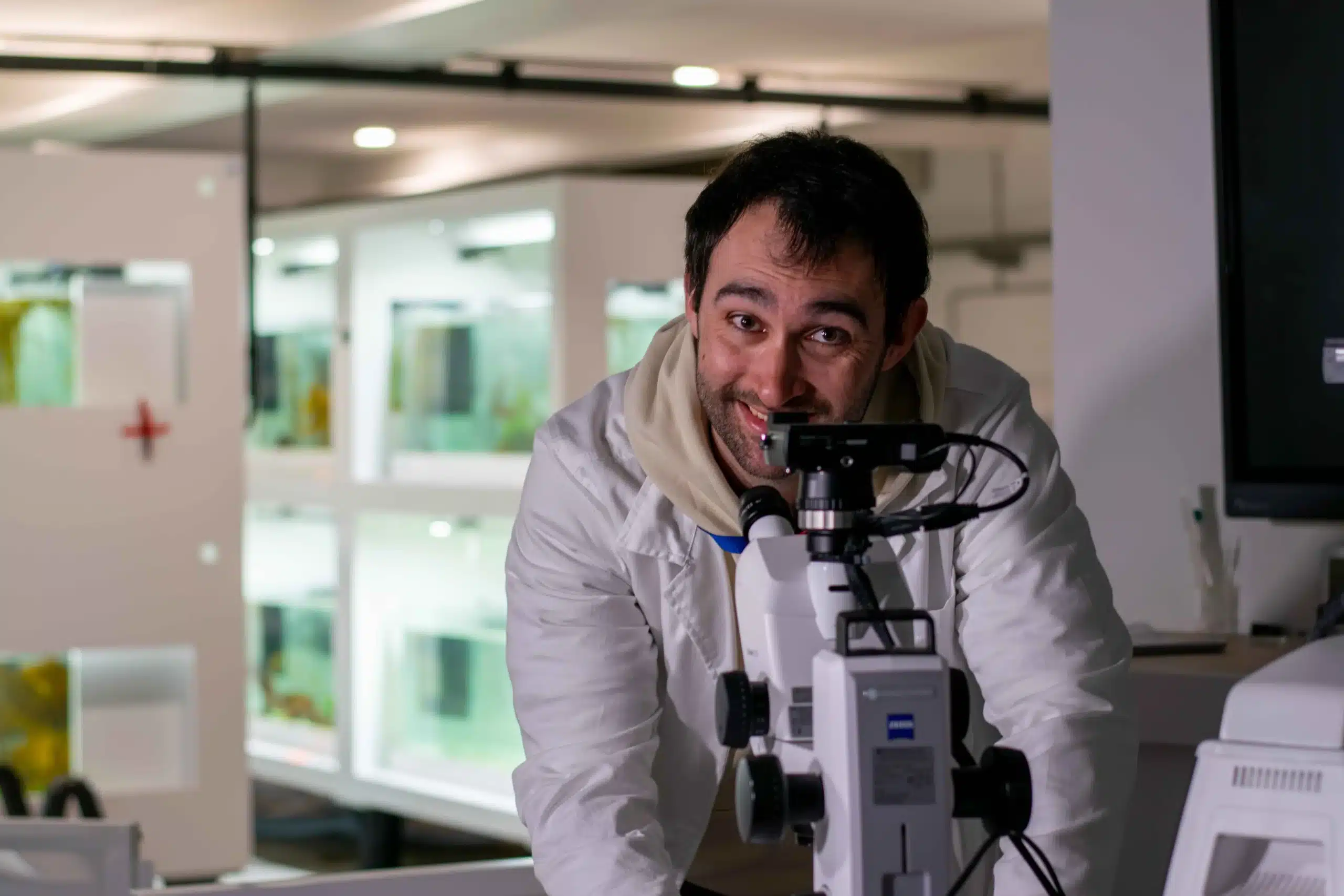 Thomas Burel, enseignant chercheur du projet ALCID, se tenant en blouse au dessus d'un microscope